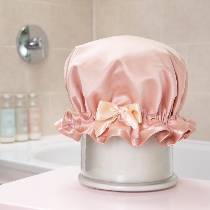 Rose gold luxury shower cap with a beige bow in a bathroom